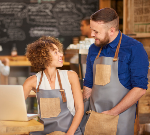 male and female business owner with laptop smiling