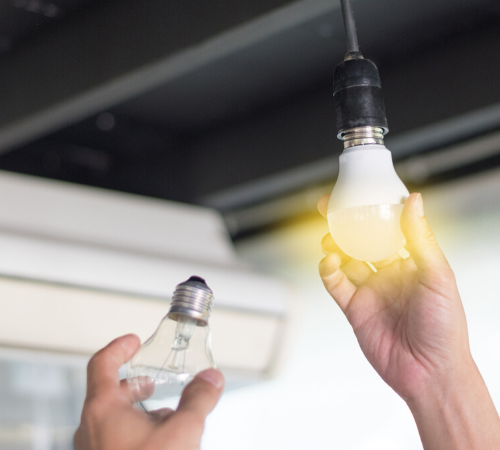 person changing light bulb to energy efficient LED bulb