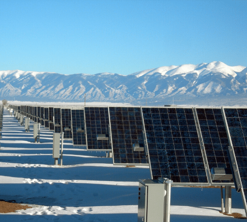 Solar panels in snow by mountains