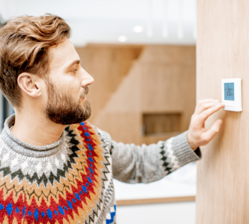 man turning down thermostat in office to save energy