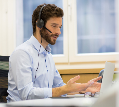 man with headset talking to laptop screen 