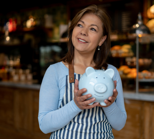 woman working in cafe holding piggy bank