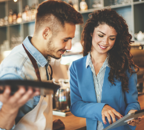 cafe owner and employee looking at tablet smiling