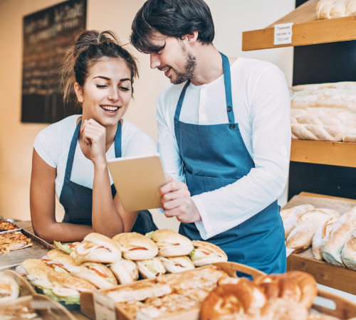 Business owners looking at a tablet in their sandwich shop