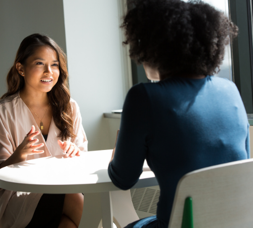two women discussing across a table 
