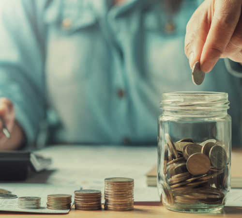 person counting money into jar with calculator