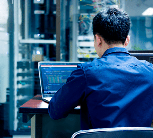 Hacker on a laptop in a sever room